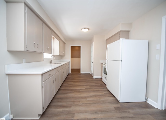 kitchen with light wood finished floors, light countertops, freestanding refrigerator, a sink, and baseboards