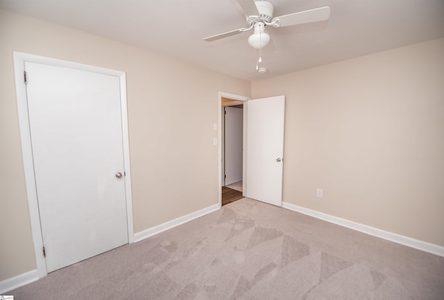 unfurnished bedroom featuring light carpet, ceiling fan, and baseboards