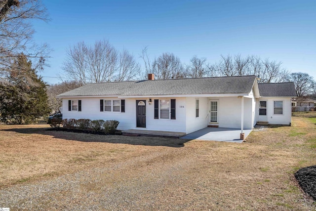 single story home featuring a patio area, a shingled roof, a chimney, and a front yard