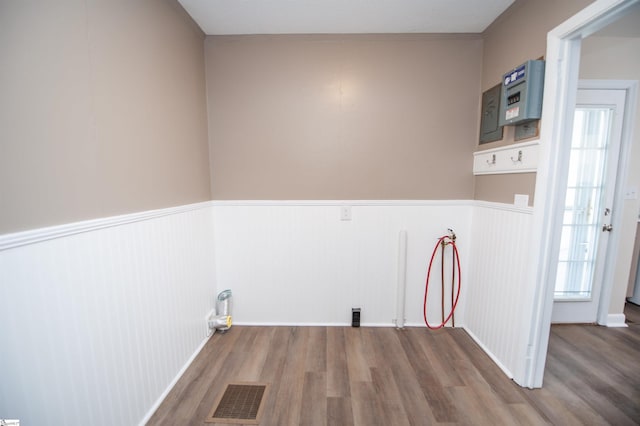 clothes washing area with a wainscoted wall, visible vents, and wood finished floors