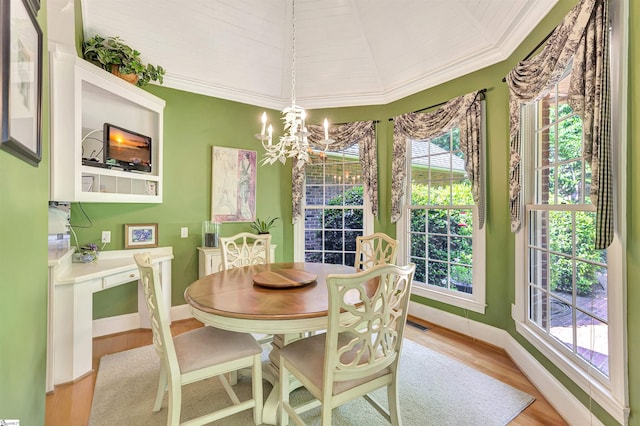 dining space featuring ornamental molding, light wood-style floors, a healthy amount of sunlight, and a notable chandelier