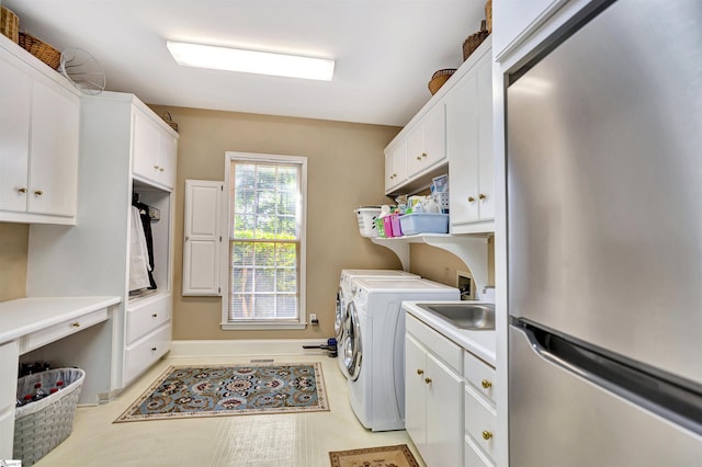 laundry area featuring cabinet space, baseboards, washer and clothes dryer, and a sink