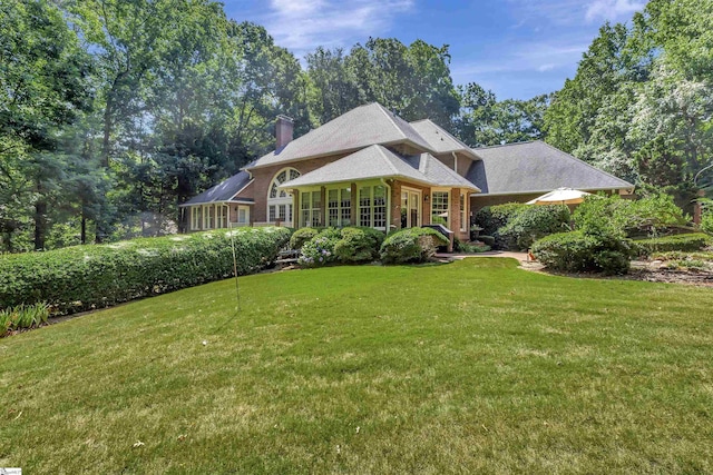 victorian-style house with brick siding, a chimney, and a front lawn