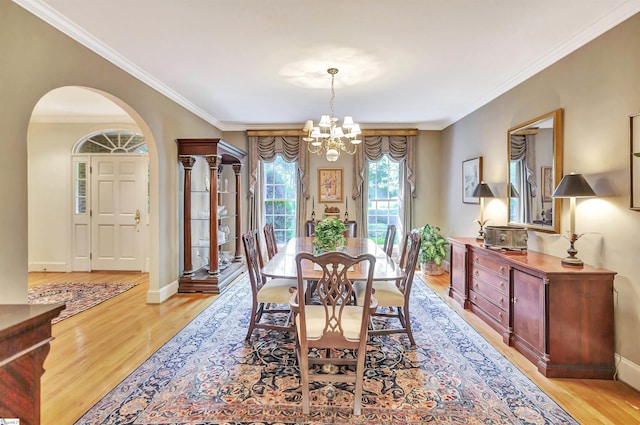 dining space with a chandelier, arched walkways, light wood-style floors, and baseboards