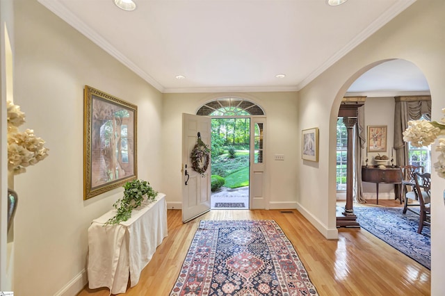 entryway featuring arched walkways, light wood finished floors, and baseboards