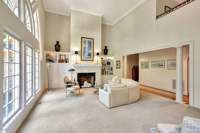 living room with ornamental molding, a high end fireplace, and decorative columns