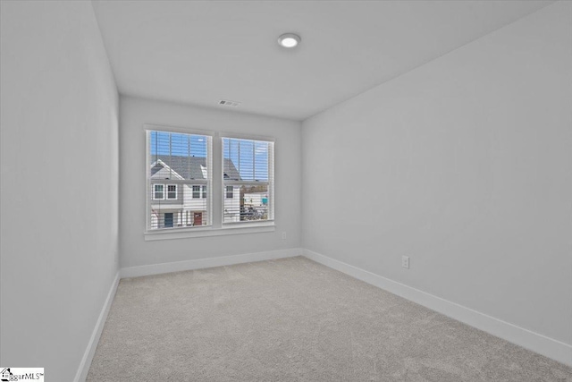 unfurnished room with light carpet, visible vents, and baseboards