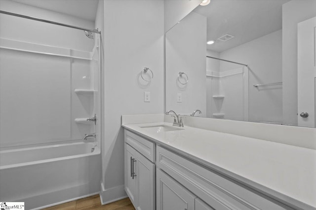 full bath with shower / bath combination, visible vents, vanity, wood finished floors, and baseboards