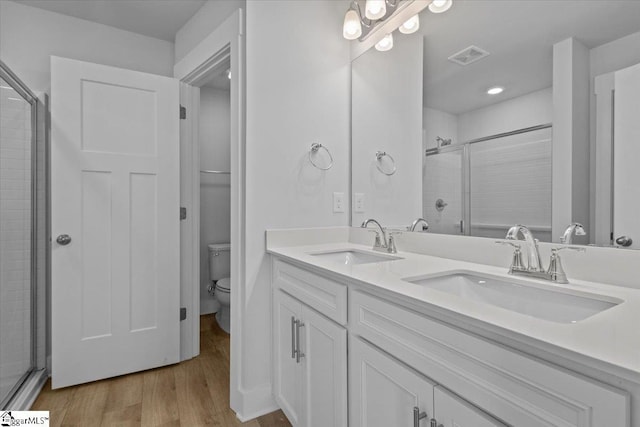 bathroom featuring toilet, a shower stall, a sink, and wood finished floors