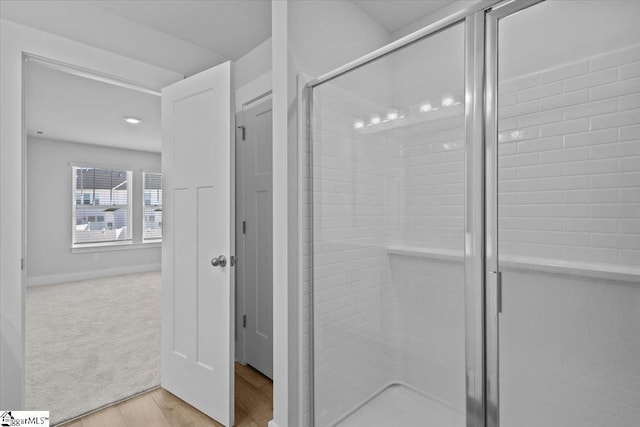 bathroom featuring a shower stall, baseboards, and wood finished floors