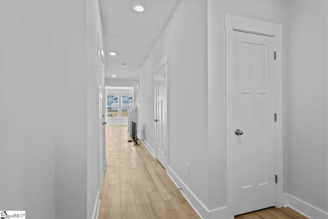 hall featuring light wood-type flooring, baseboards, and recessed lighting