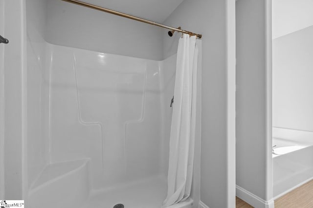 bathroom with a shower stall and wood finished floors