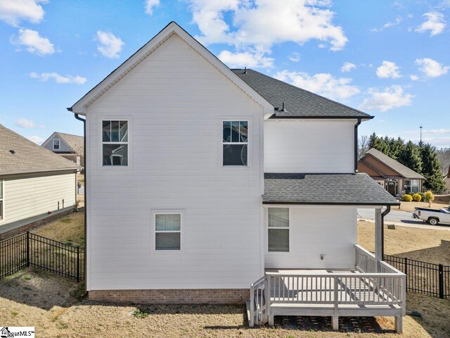 back of property with roof with shingles, fence, and a wooden deck