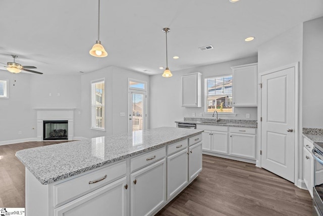 kitchen featuring dark wood-style floors, a fireplace, visible vents, white cabinets, and a sink