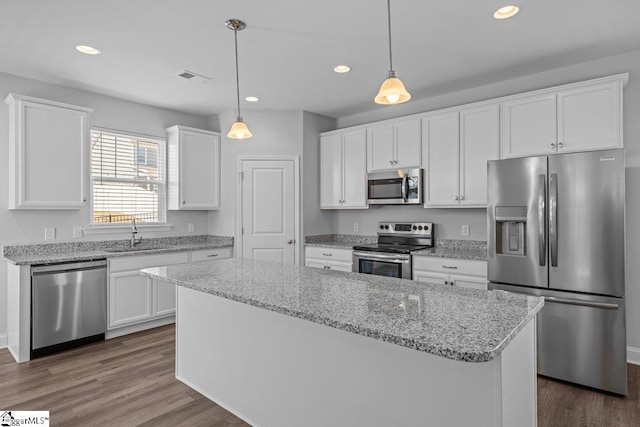 kitchen featuring visible vents, appliances with stainless steel finishes, a center island, white cabinetry, and a sink