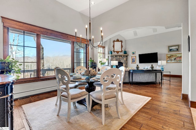 dining room featuring lofted ceiling, hardwood / wood-style flooring, baseboards, baseboard heating, and an inviting chandelier