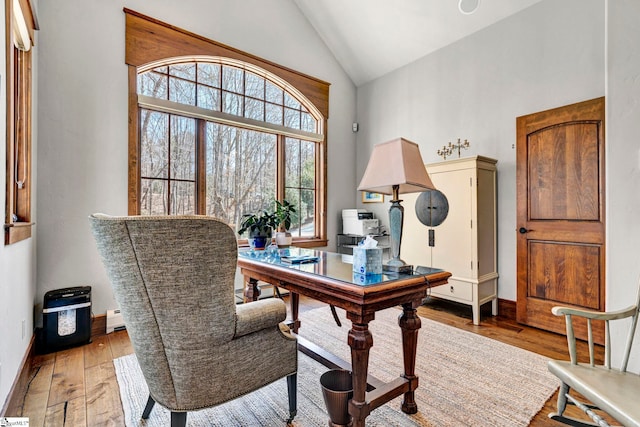 home office featuring a baseboard heating unit, high vaulted ceiling, light wood-style flooring, and baseboards