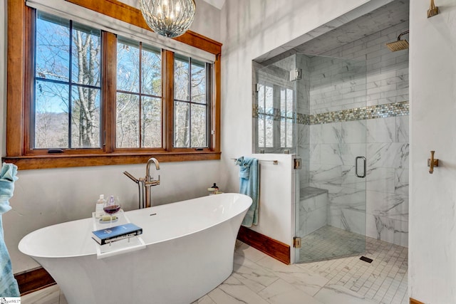 bathroom with baseboards, marble finish floor, a freestanding tub, a shower stall, and a chandelier