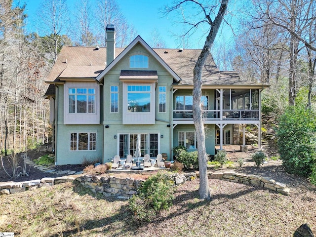 back of house with a patio, a chimney, stucco siding, a shingled roof, and a sunroom