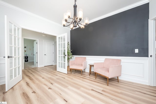 unfurnished room featuring french doors, crown molding, a notable chandelier, wainscoting, and wood finished floors