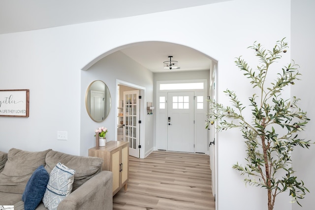 foyer with light wood-style floors and arched walkways