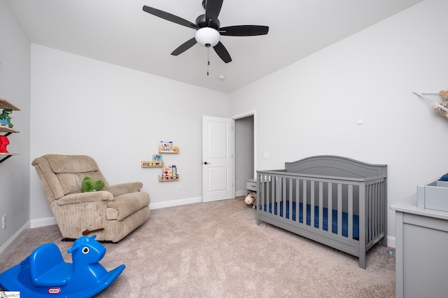 carpeted bedroom with a nursery area, ceiling fan, and baseboards