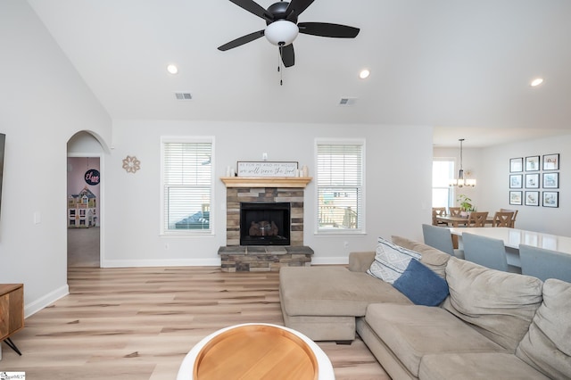 living room featuring a stone fireplace, light wood-style flooring, and visible vents