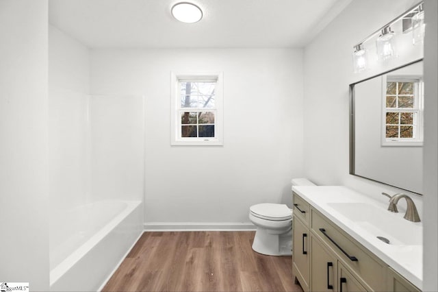 bathroom with toilet, baseboards, wood finished floors, and vanity