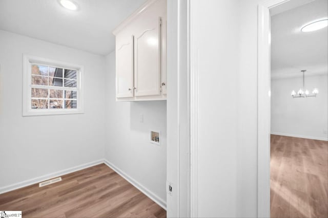 washroom featuring washer hookup, a notable chandelier, visible vents, wood finished floors, and baseboards