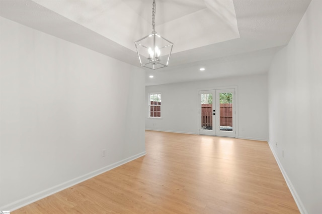 unfurnished room with french doors, baseboards, light wood finished floors, and an inviting chandelier