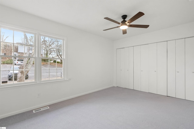 unfurnished bedroom featuring ceiling fan, carpet floors, visible vents, baseboards, and a closet