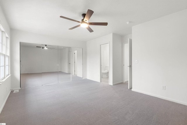 carpeted spare room featuring ceiling fan, visible vents, and baseboards