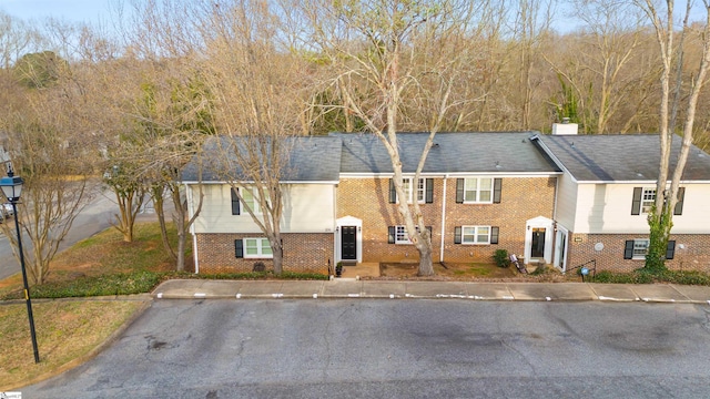 view of front of home with brick siding and a chimney