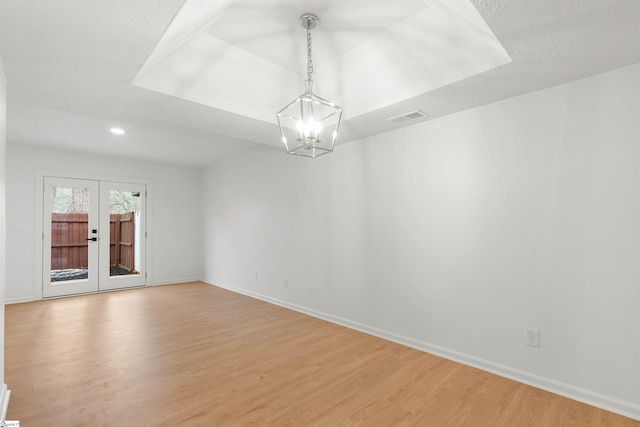 empty room featuring french doors, visible vents, light wood-style flooring, and baseboards