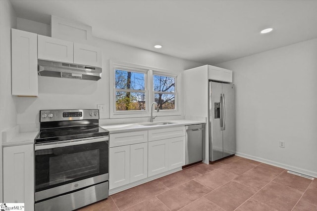 kitchen with appliances with stainless steel finishes, white cabinets, a sink, and under cabinet range hood