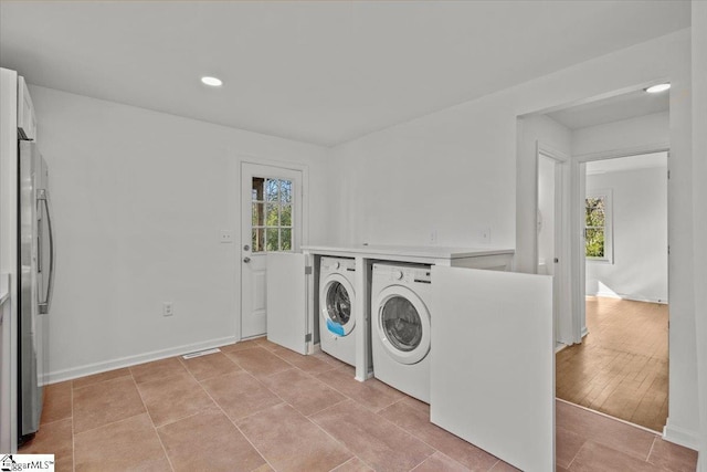 laundry area with light tile patterned floors, baseboards, and washer and clothes dryer