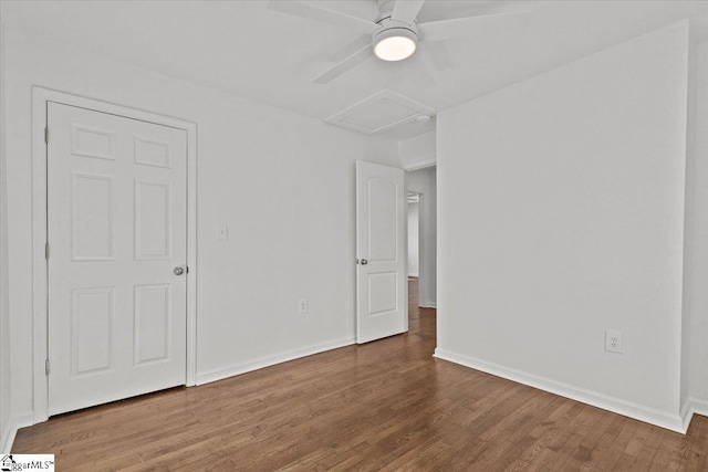 empty room featuring attic access, baseboards, and wood finished floors