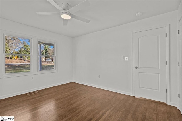 spare room with a ceiling fan, wood finished floors, visible vents, and baseboards