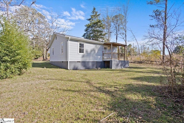 view of side of home with crawl space, covered porch, and a yard