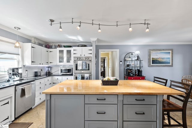 kitchen with appliances with stainless steel finishes, gray cabinets, crown molding, a kitchen bar, and wooden counters