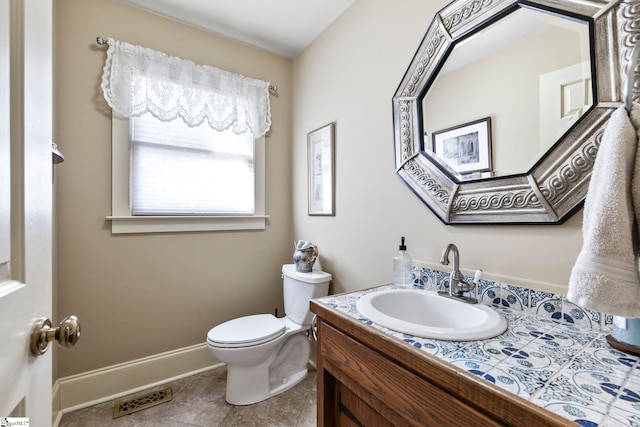 half bathroom with toilet, vanity, visible vents, baseboards, and tile patterned floors