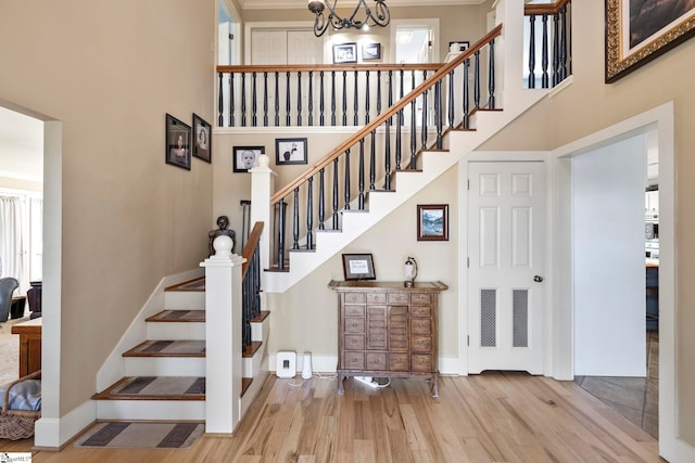 stairs featuring a towering ceiling, baseboards, and wood finished floors