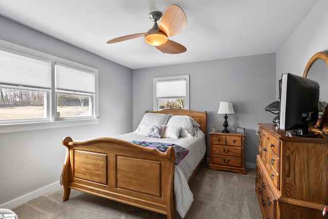 carpeted bedroom featuring a ceiling fan, multiple windows, and baseboards