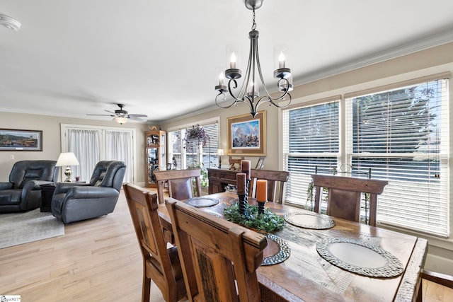 dining room featuring crown molding, light wood-style flooring, and ceiling fan with notable chandelier