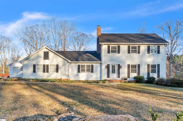 colonial-style house featuring a chimney and a front yard