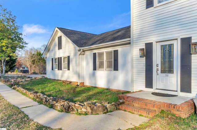 doorway to property with roof with shingles