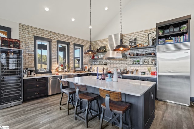 kitchen featuring open shelves, appliances with stainless steel finishes, wall chimney exhaust hood, and wood finished floors