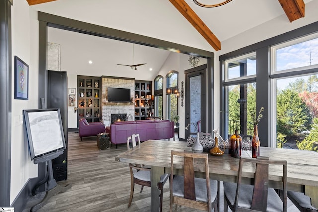 dining space featuring built in shelves, vaulted ceiling with beams, recessed lighting, a brick fireplace, and wood finished floors