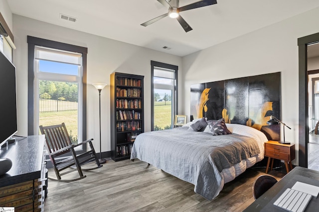 bedroom with visible vents, multiple windows, and wood finished floors