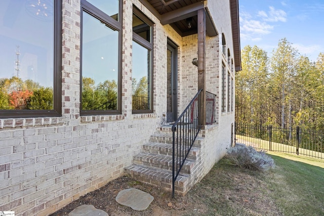 entrance to property featuring fence and brick siding